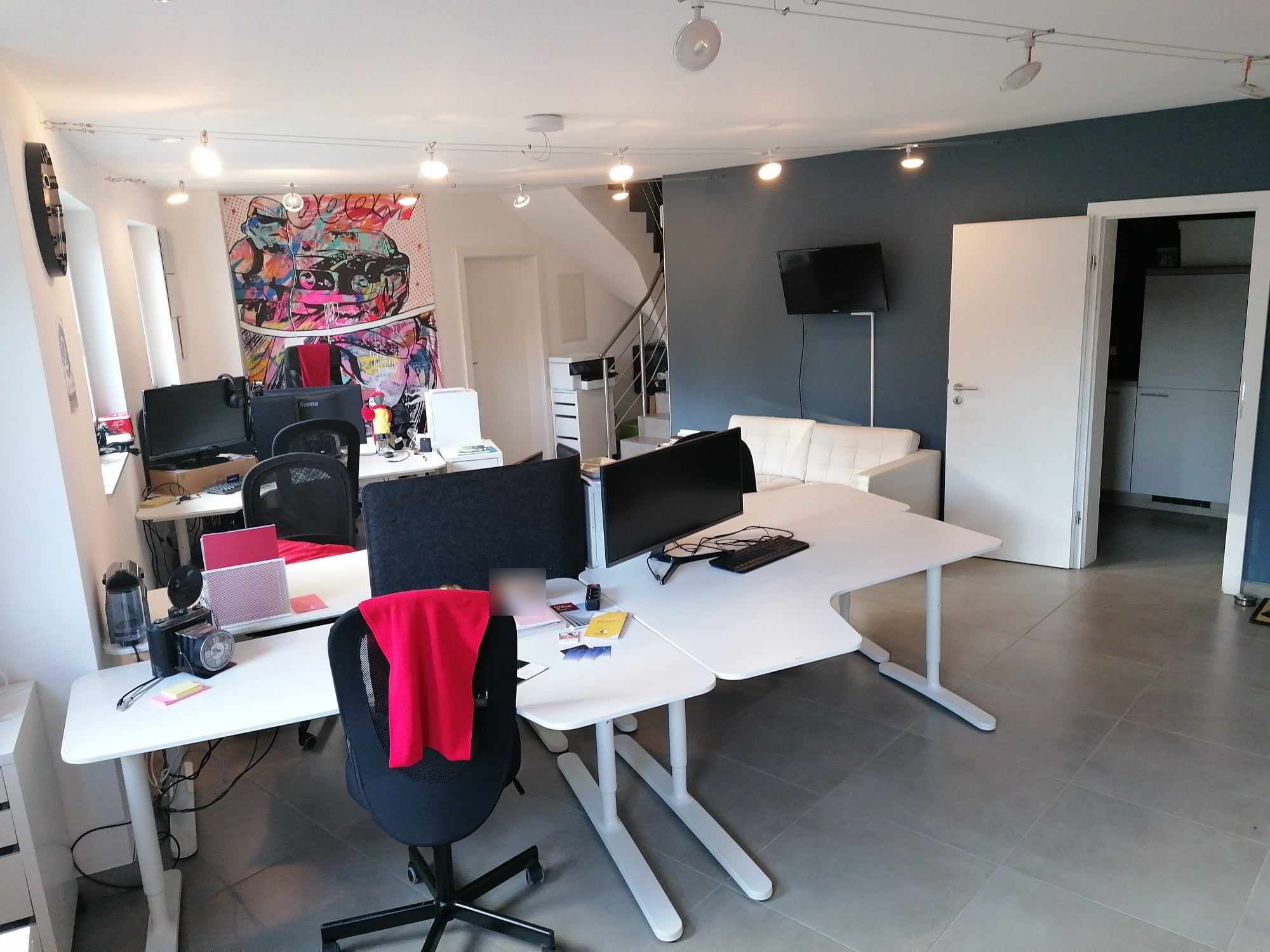 L'open space de 2B Space : bureaux blancs, éclairage sur câbles, canapé et mur bleu ardoise
